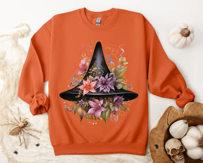 Whimsical Witch Hat Sweatshirt with a watercolor illustration of a black witch hat surrounded by flowers in purple, pink, and green. Available in multiple dark and light colors and sizes. Gildan 18000 sweatshirt in Orange. ReadyShirtAim.com