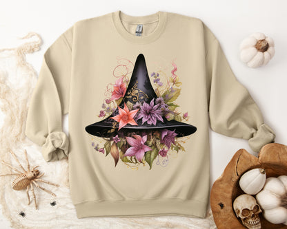 Whimsical Witch Hat Sweatshirt with a watercolor illustration of a black witch hat surrounded by flowers in purple, pink, and green. Available in multiple dark and light colors and sizes. Gildan 18000 sweatshirt in Sand. ReadyShirtAim.com