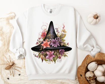 Whimsical Witch Hat Sweatshirt with a watercolor illustration of a black witch hat surrounded by flowers in purple, pink, and green. Available in multiple dark and light colors and sizes. Gildan 18000 sweatshirt in white. ReadyShirtAim.com