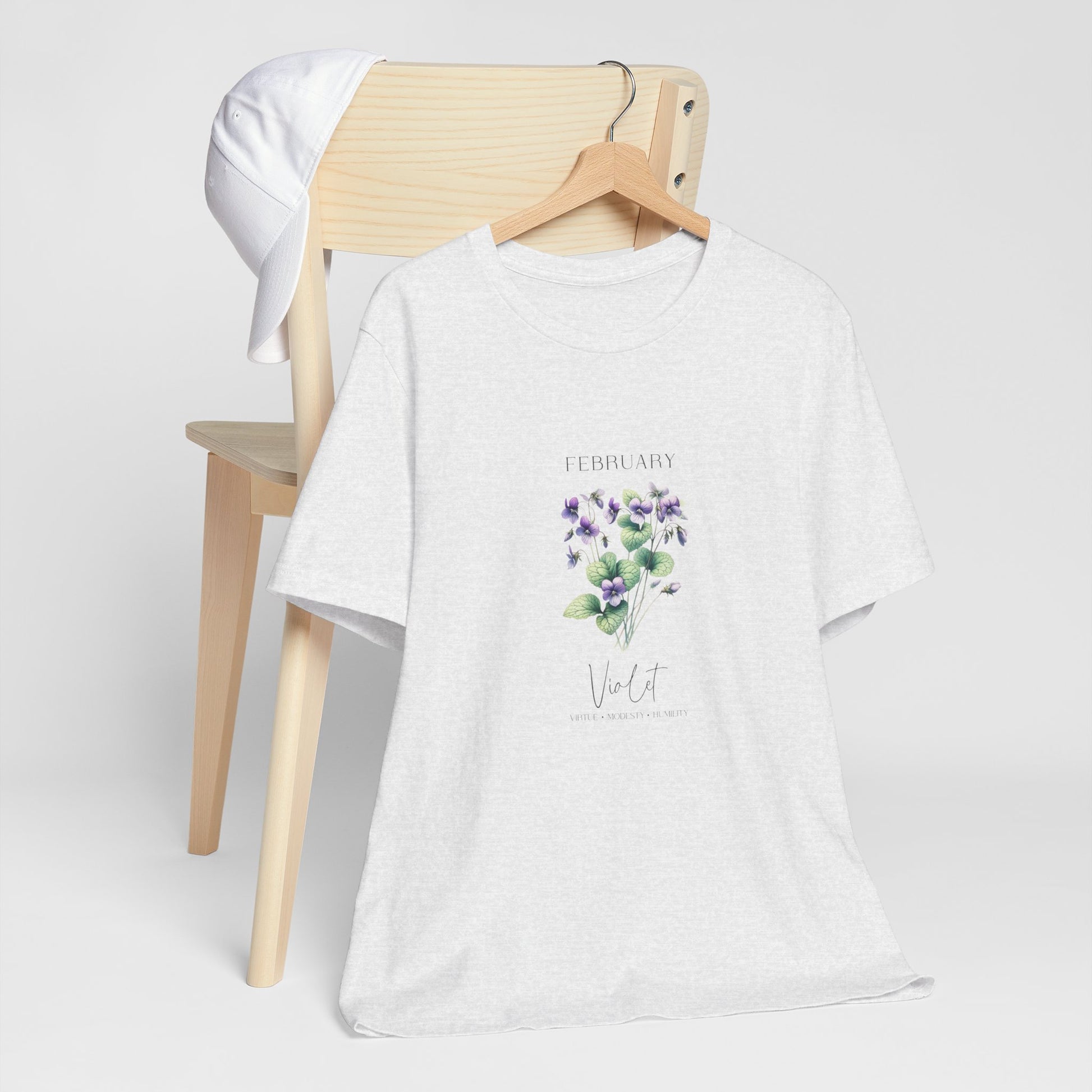 A t-shirt featuring a beautiful violet for February with traits Virtue, Modesty, Humility. Perfect for February birthdays and floral art lovers. Comfortable and stylish for casual outings or celebrations. Bella+Canvas 3001 t-shirt in ash. ReadyShirtAim.com