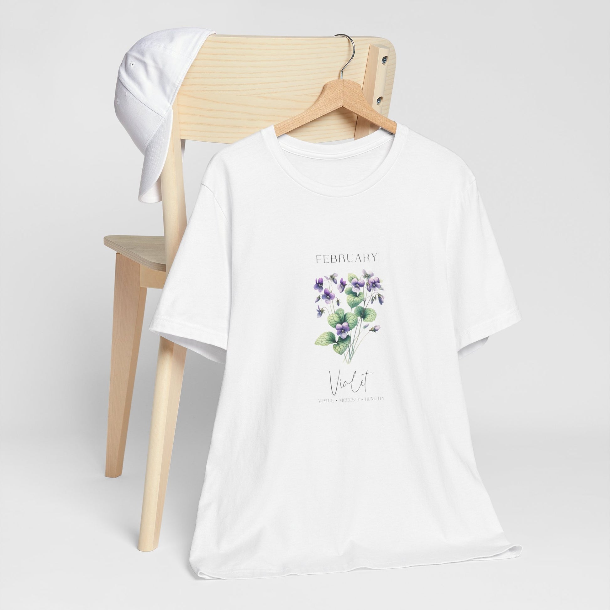 A t-shirt featuring a beautiful violet for February with traits Virtue, Modesty, Humility. Perfect for February birthdays and floral art lovers. Comfortable and stylish for casual outings or celebrations. Bella+Canvas 3001 t-shirt in white. ReadyShirtAim.com