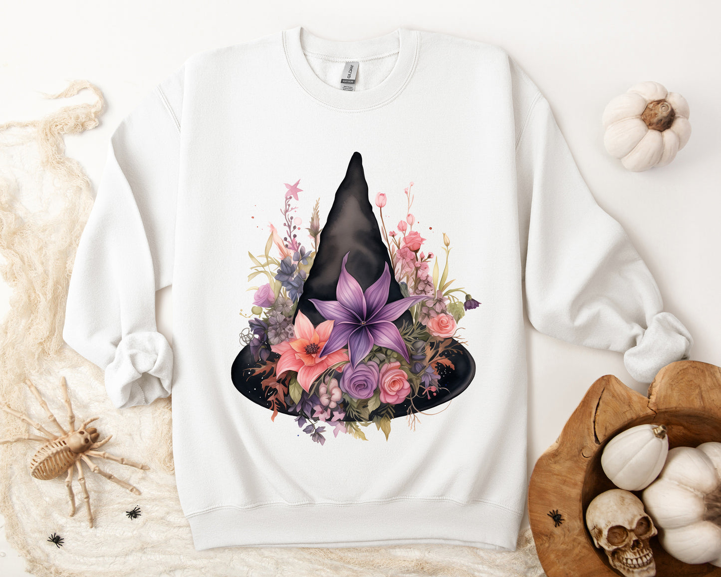 Feminine Witchy Vibes Boho Halloween Sweatshirt for her, featuring a watercolor illustration of a black witch hat and flowers in purple, pink, and green. Available in multiple dark and light colors and sizes. Gildan 18000 sweatshirt in white. ReadyShirtAim.com