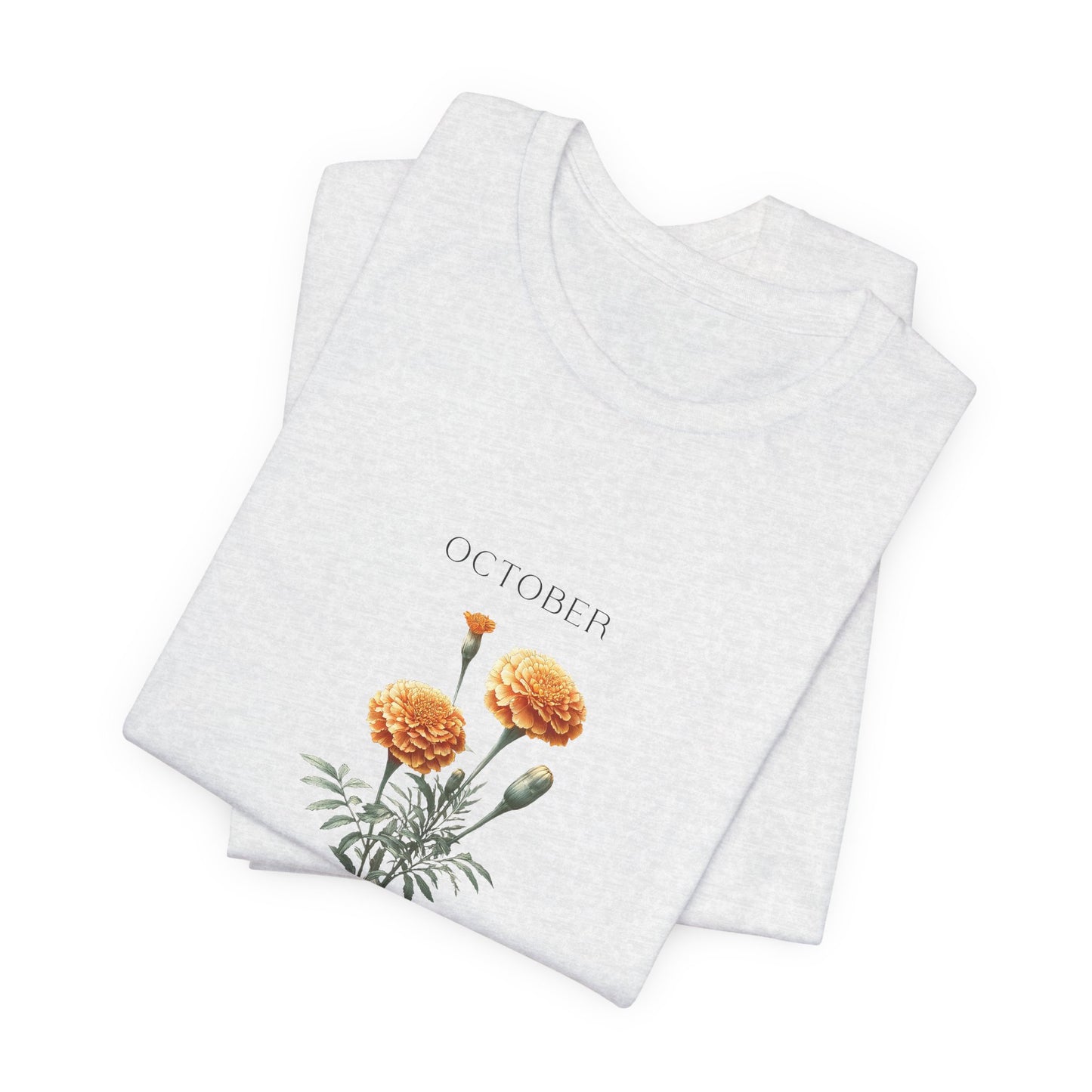 A t-shirt featuring a beautiful marigold for October with traits Passion, Creativity, Courage. Perfect for October birthdays and floral art lovers. Comfortable and stylish for casual outings or celebrations. Bella+Canvas 3001 t-shirt in ash. ReadyShirtAim.com