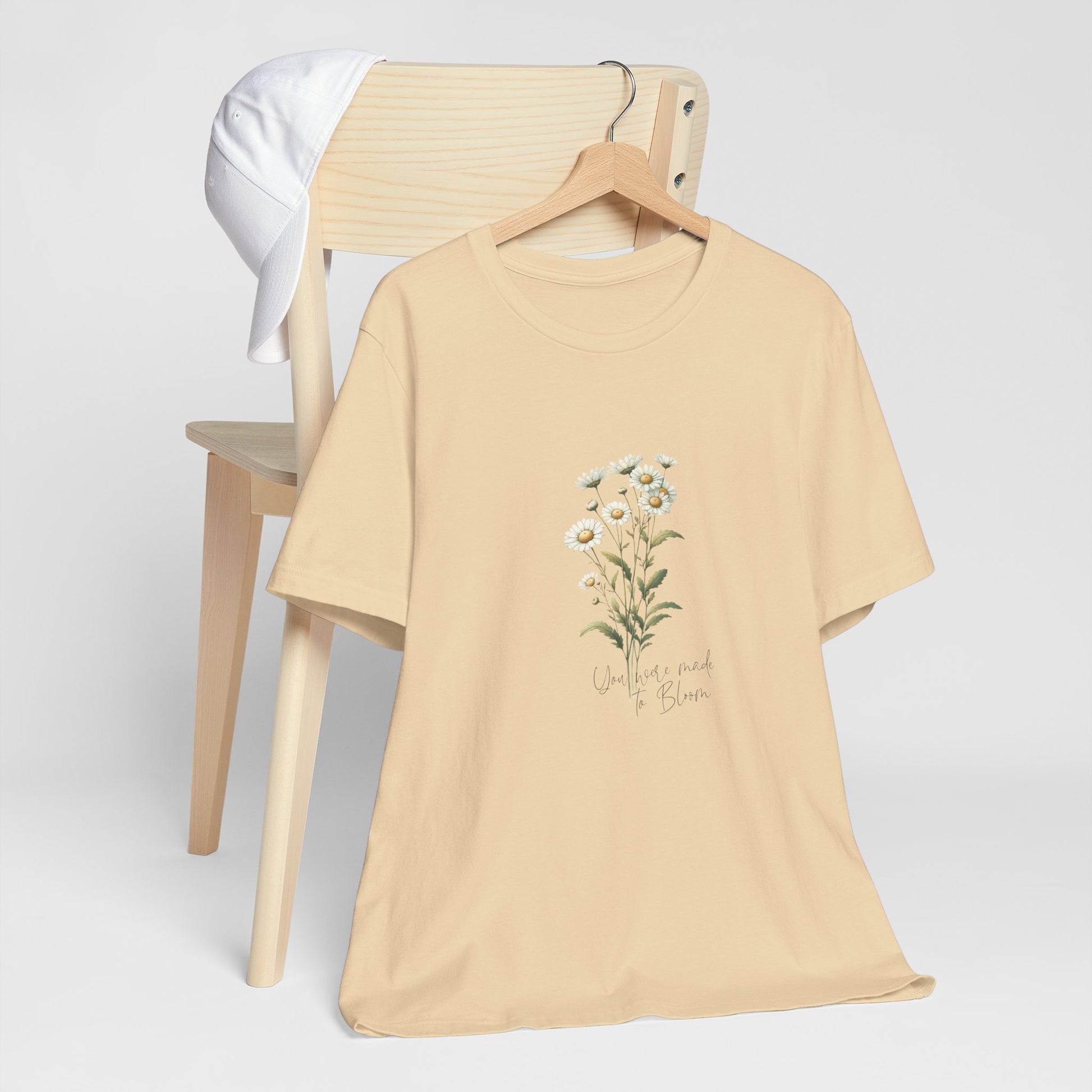 A t-shirt featuring a beautiful daisy for April with the quote “You were made to bloom.” Perfect for April birthdays and floral art lovers. Comfortable and stylish for casual outings or celebrations. Bella+Canvas 3001 t-shirt in soft cream. ReadyShirtAim.com