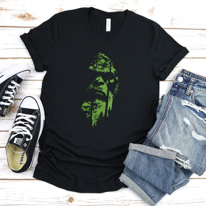 A t-shirt featuring an enigmatic cryptid design of Bigfoot's face, perfect for Bigfoot enthusiasts, cryptid fans, and adventure seekers. Comfortable and stylish for casual outings or cryptid conventions. Bella+Canvas 3001 t-shirt in black. ReadyShirtAim.com