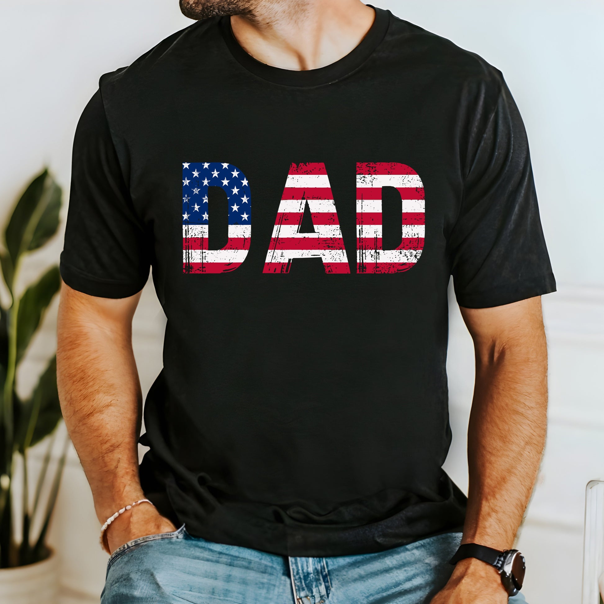 A dark t-shirt with bold "DAD" text filled with the American flag and a grunge texture. This patriotic shirt is perfect for Father's Day or any occasion to honor dad. Made from soft, breathable cotton for ultimate comfort. Available in multiple dark colors and sizes. Bella+Canvas 3001 t-shirt. ReadyShirtAim.com