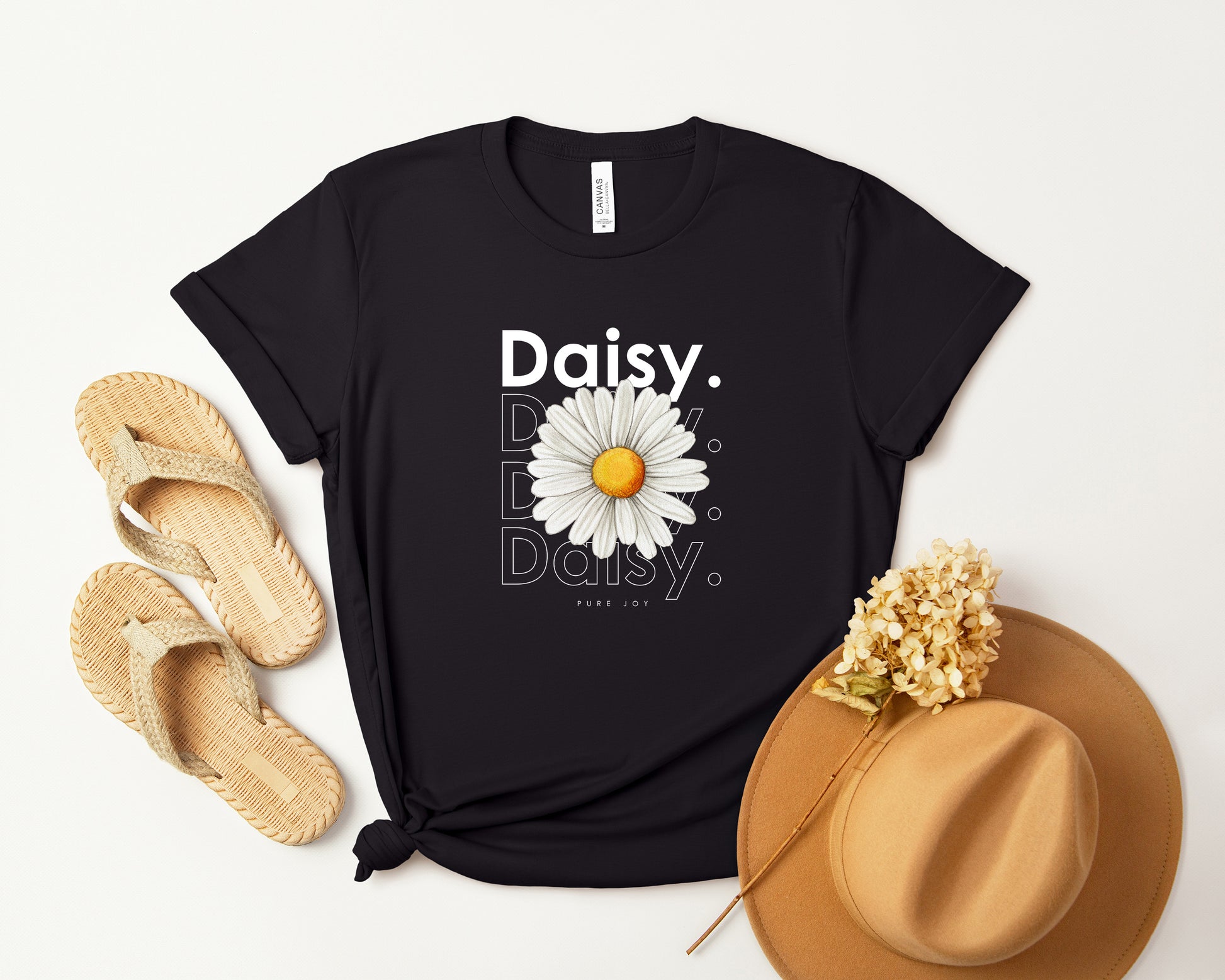 A photo-realistic white daisy t-shirt with a bold contemporary floral design and the caption "Pure Joy." Perfect for daisy lovers, botanical enthusiasts, and nature lovers. Bella+Canvas 3001 t-shirt in black. ReadyShirtAim.com