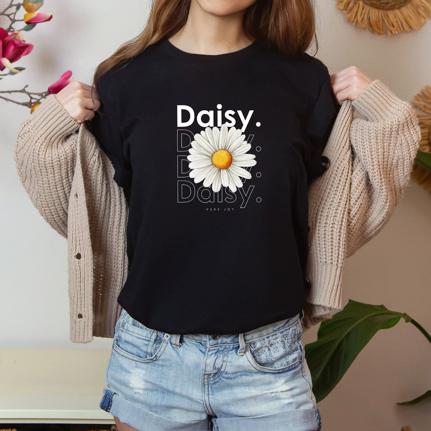 A photo-realistic white daisy t-shirt with a bold contemporary floral design and the caption "Pure Joy." Perfect for daisy lovers, botanical enthusiasts, and nature lovers. Bella+Canvas 3001 t-shirt in black. ReadyShirtAim.com