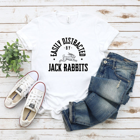  vintage typeface t-shirt with a hand-drawn sketch of a jack rabbit and the caption "Easily Distracted by Jack Rabbits." Perfect for rabbit lovers, wildlife watchers, and nature enthusiasts.  Bella+Canvas 3001 t-shirt in white. ReadyShirtAim.com