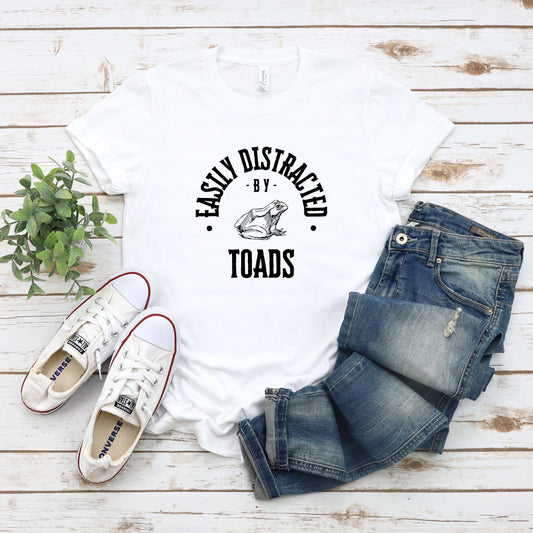 A vintage typeface t-shirt with a hand-drawn sketch of a toad and the caption "Easily Distracted by Toads." Perfect for toad lovers, herpetologists, and wildlife enthusiasts. Bella+Canvas 3001 t-shirt in white. ReadyShirtAim.com