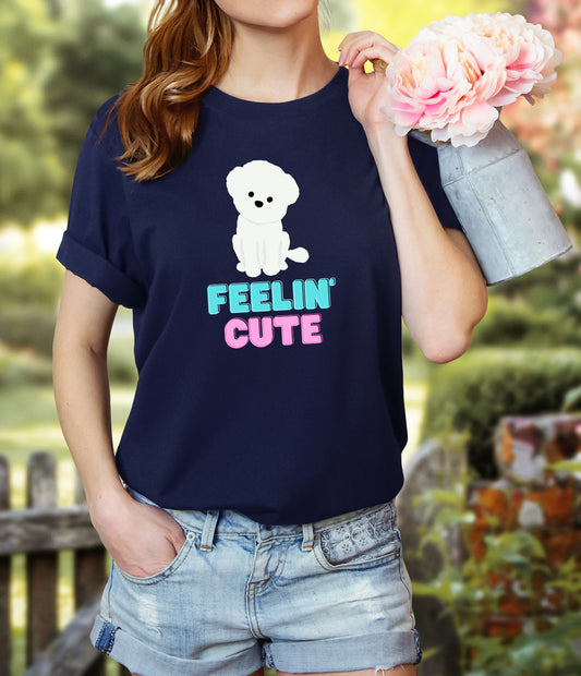 "Feelin' Cute" Maltese Dog T-Shirt for Women with a cartoon graphic of a Maltese dog sitting with its head cocked to the side and bold "Feelin' Cute" text in aqua and pink. Ideal for female Maltese dog lovers. Bella+Canvas 3001 t-shirt in navy. ReadyShirtAim.com