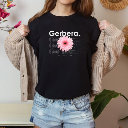 A photo-realistic pink on pink gerbera t-shirt with a bold contemporary floral design and the caption "Soft Splendor." Perfect for gerbera lovers, botanical enthusiasts, and nature lovers. Bella+Canvas 3001 t-shirt in black. ReadyShirtAim.com