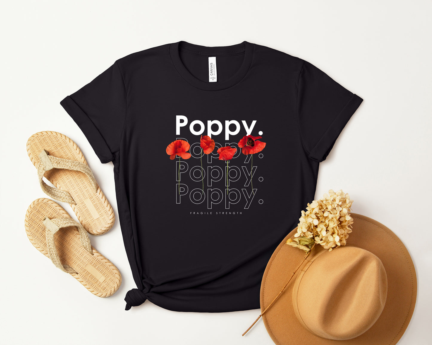 A photo-realistic red poppy t-shirt with a bold contemporary floral design and the caption "Fragile Strength." Perfect for poppy lovers, botanical enthusiasts, and nature lovers. Bella+Canvas 3001 t-shirt in black. ReadyShirtAim.com