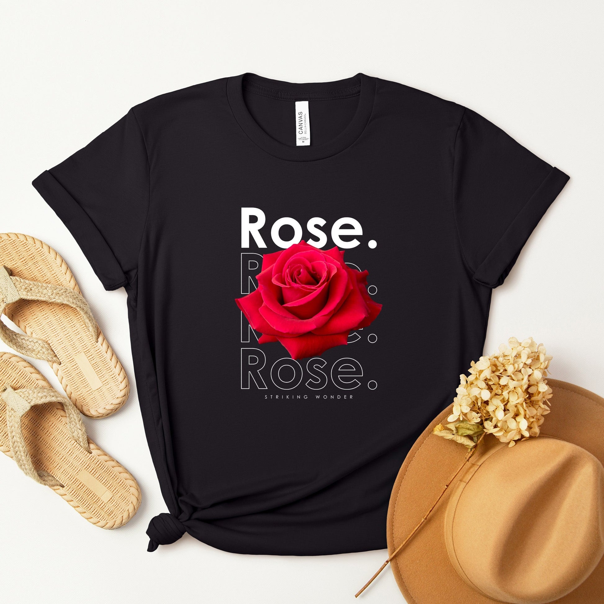 A t-shirt featuring a stunning deep red photo-realistic rose with the theme 'Striking Wonder.' Perfect for those who adore bold floral art and nature. Comfortable and stylish for casual outings or celebrations. Bella+Canvas 3001 t-shirt in black. ReadyShirtAim.com