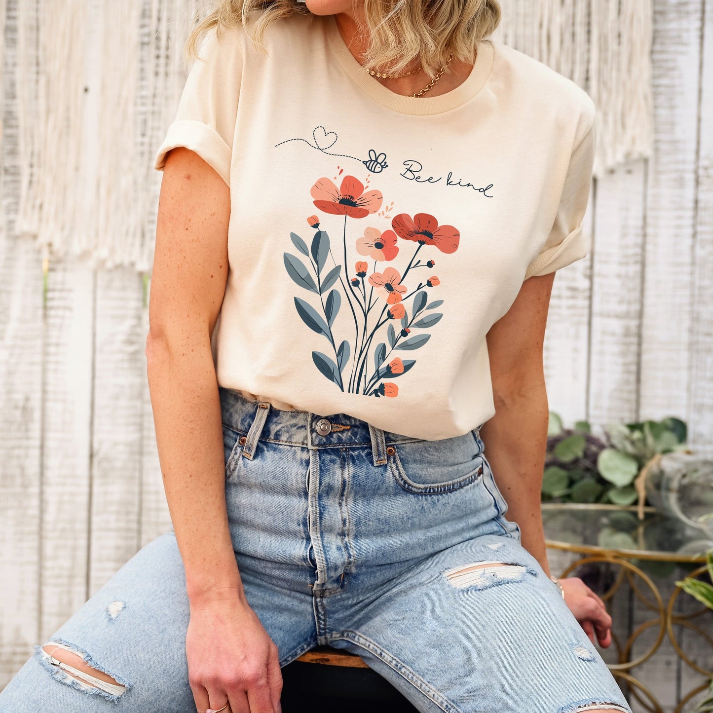 A Boho Scandinavian floral t-shirt with a simple flower design and the caption "Bee Kind." Perfect for compassionate souls, garden lovers, and nature enthusiasts. Bella+Canvas 3001 t-shirt in soft cream. ReadyShirtAim.com