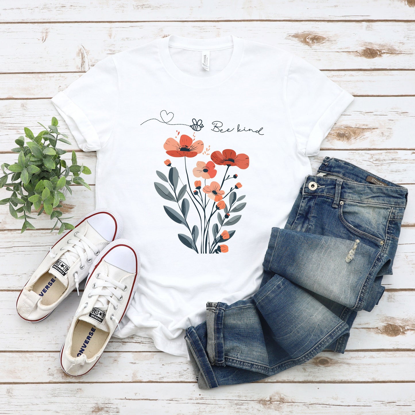 A Boho Scandinavian floral t-shirt with a simple flower design and the caption "Bee Kind." Perfect for compassionate souls, garden lovers, and nature enthusiasts. Bella+Canvas 3001 t-shirt in white. ReadyShirtAim.com