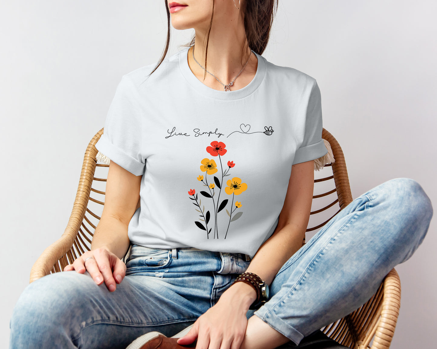 A Boho Scandinavian floral t-shirt with a simple flower design and the caption "Live Simply." Perfect for minimalist souls, garden lovers, and nature enthusiasts. Bella+Canvas 3001 t-shirt in silver. ReadyShirtAim.com