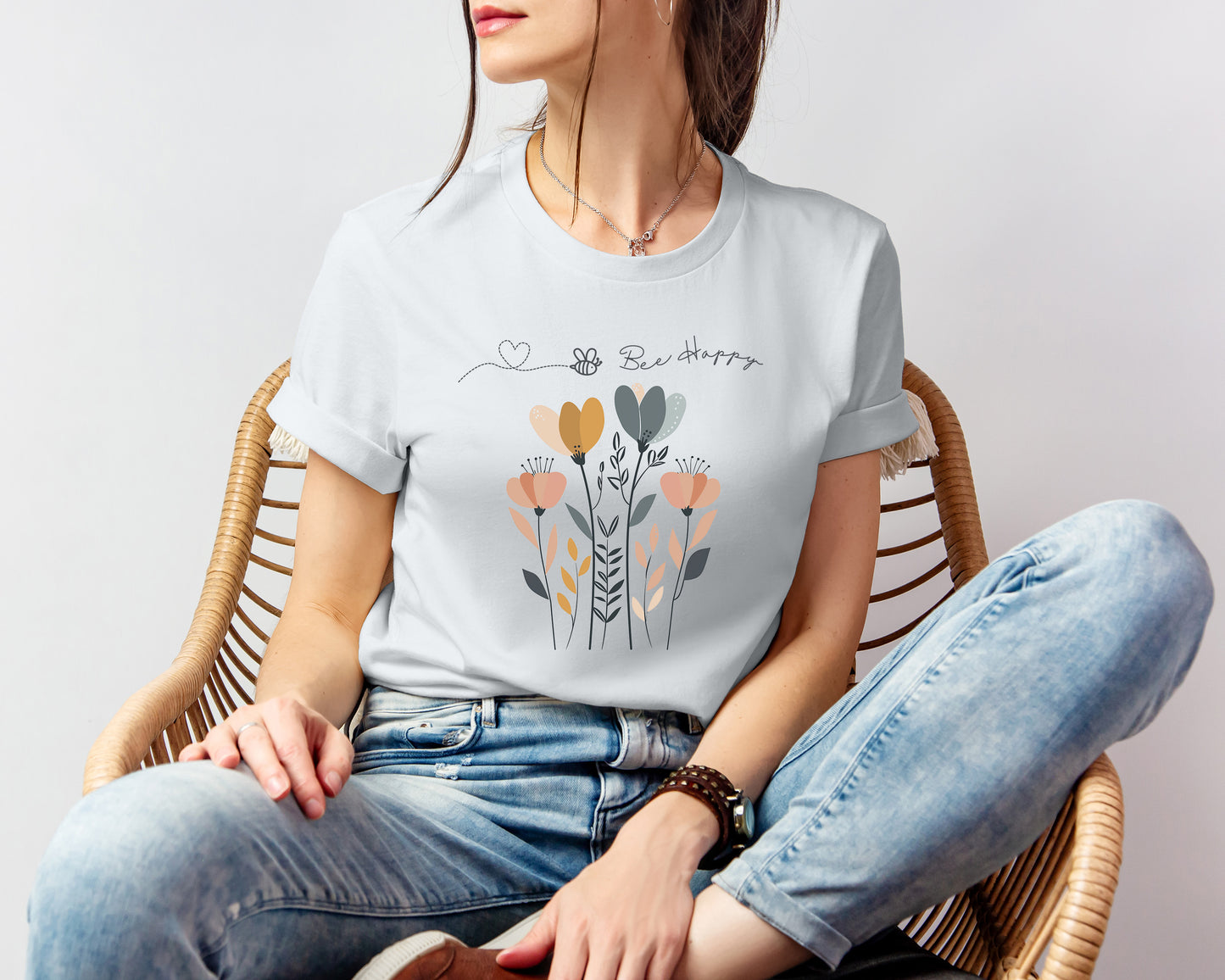 A Boho Scandinavian floral t-shirt with a simple flower design and the caption "Bee Happy." Perfect for spreading positive vibes, garden lovers, and nature enthusiasts. Bella+Canvas 3001 t-shirt in silver. ReadyShirtAim.com